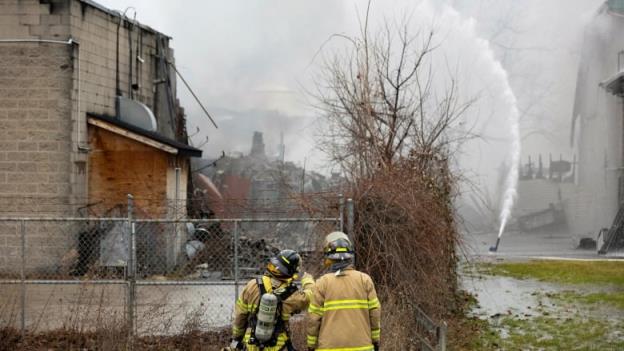 Two firefighters look in the direction of a hazardous waste management company in St. Catharines, Ont., wher<em></em>e they're trying to put out a fire.