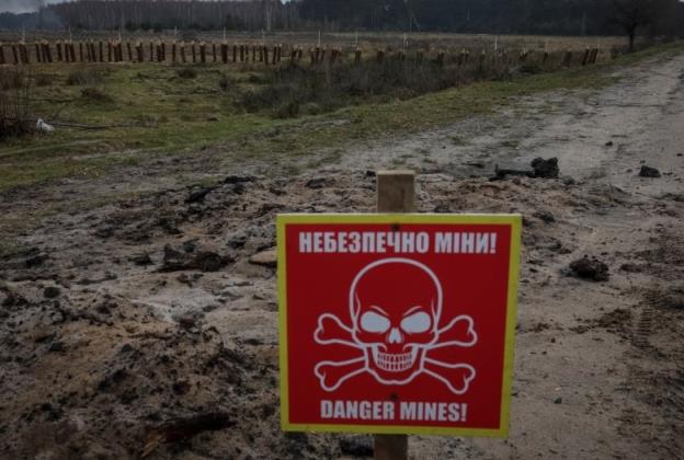 A mine danger sign and anti-tank co<em></em>nstructions are seen in a muddy field
