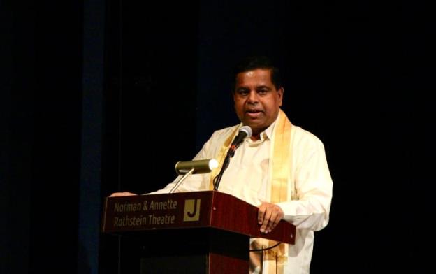 Man stands in traditio<em></em>nal white and gold Tamil clothing and gives a speech at the Norman Rothstein Theatre in Vancouver. 