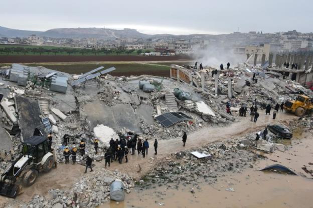 An aerial view of workers standing on a large pile of co<em></em>ncrete rubble.